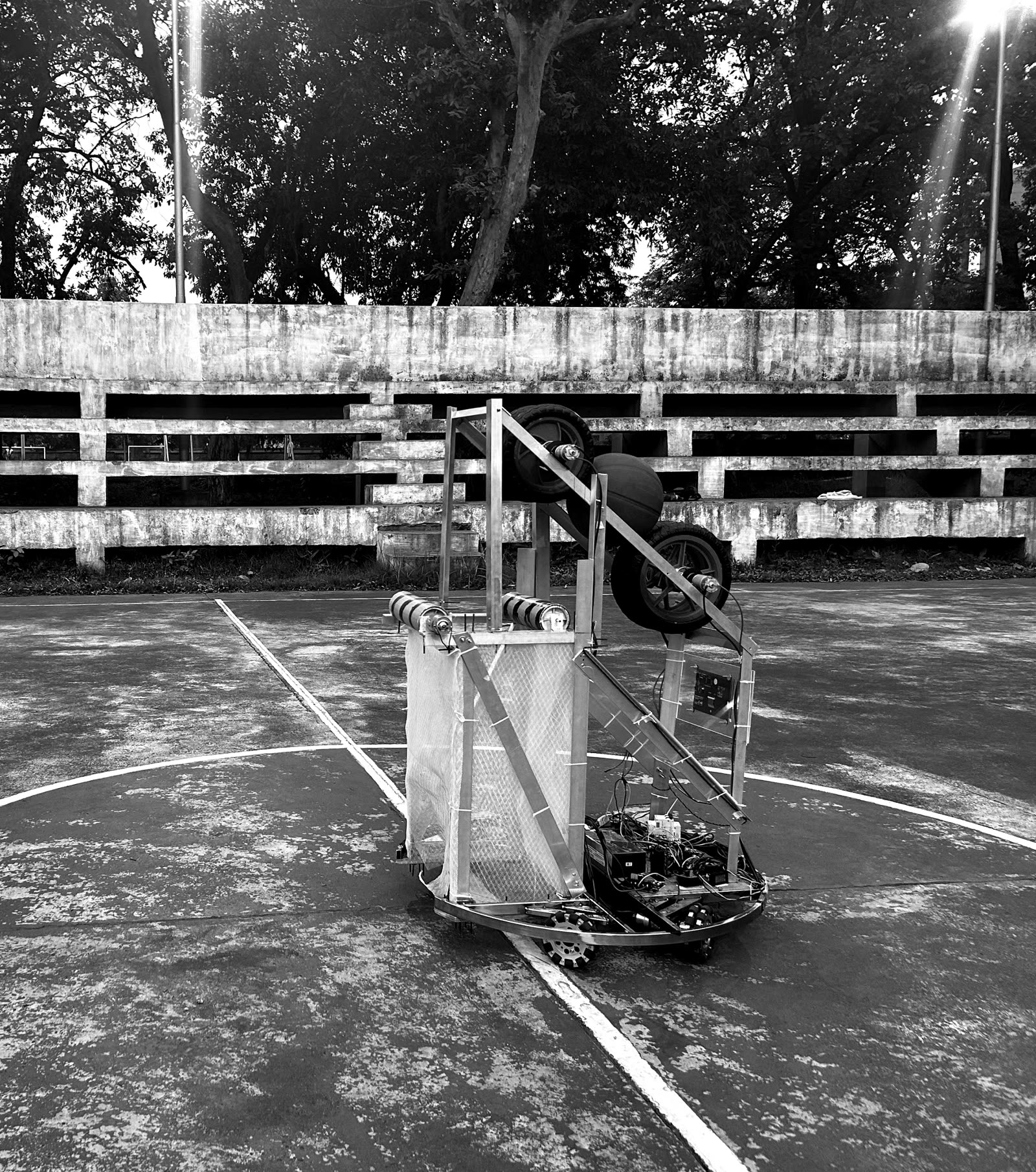 The Robocon competition robot on an outdoor basketball court with a ball loaded into its launcher