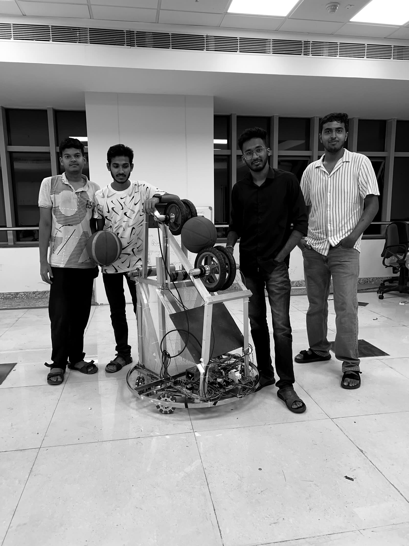 Four team members standing with the completed competition robot, holding basketballs