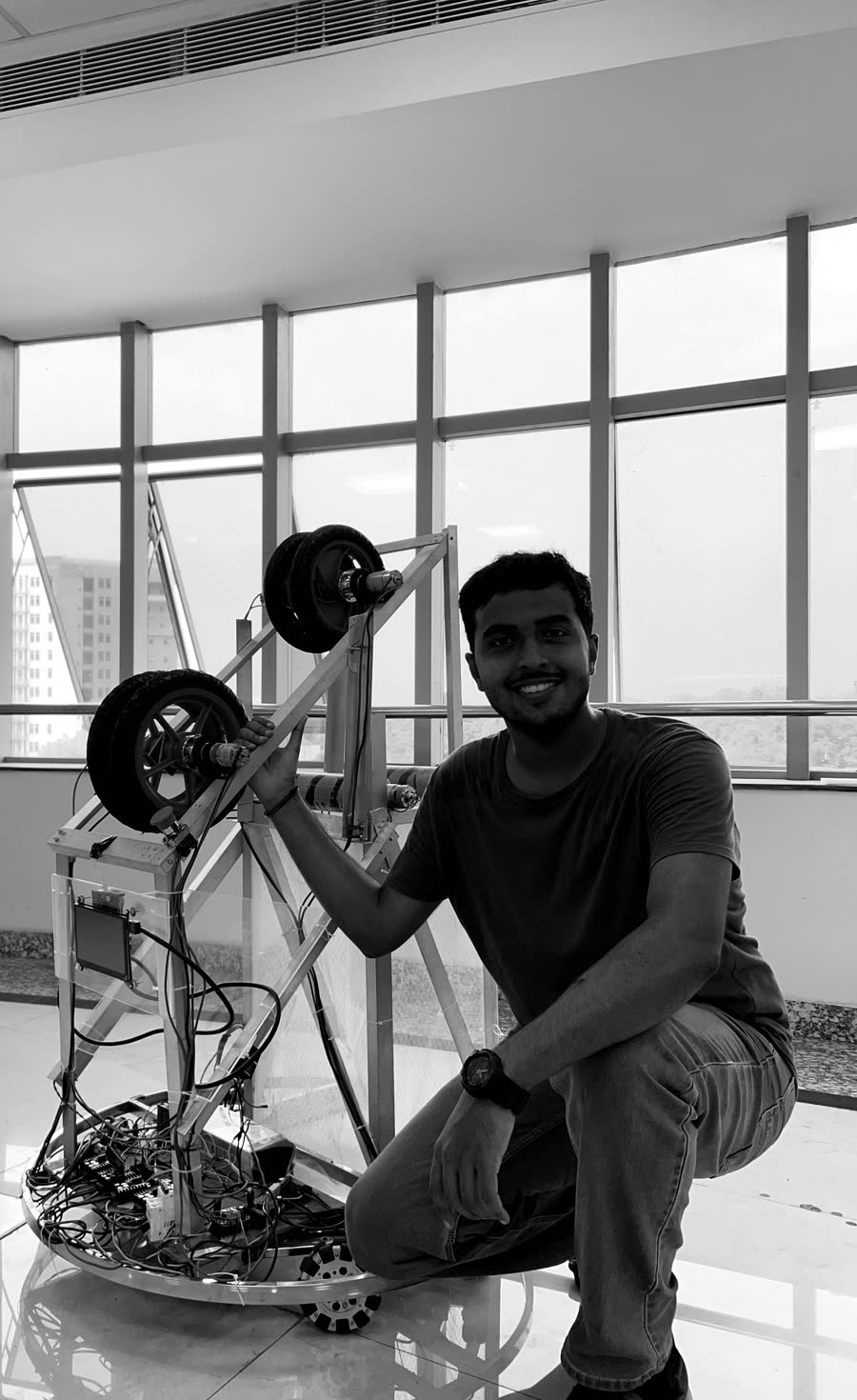 Veerendra R. Patil crouched beside the Robocon competition robot in the RoboCell lab