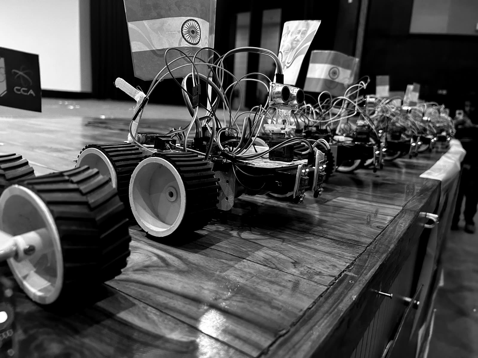 A row of identical student-built line-following robots lined up on a stage at a RoboCell workshop